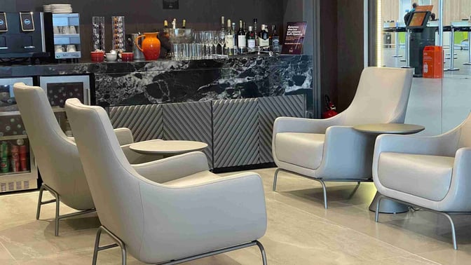 The BRT Lounge at Presidente João Figueiredo Airport features a seating area with armchairs and a self-serve beverage station.
