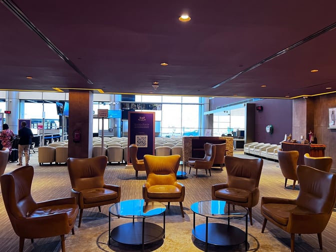 The Al Ula Lounge at Prince Abdul Majeed bin Abdulaziz Airport features comfortable seating with armchairs and tables, adjacent to the boarding area.