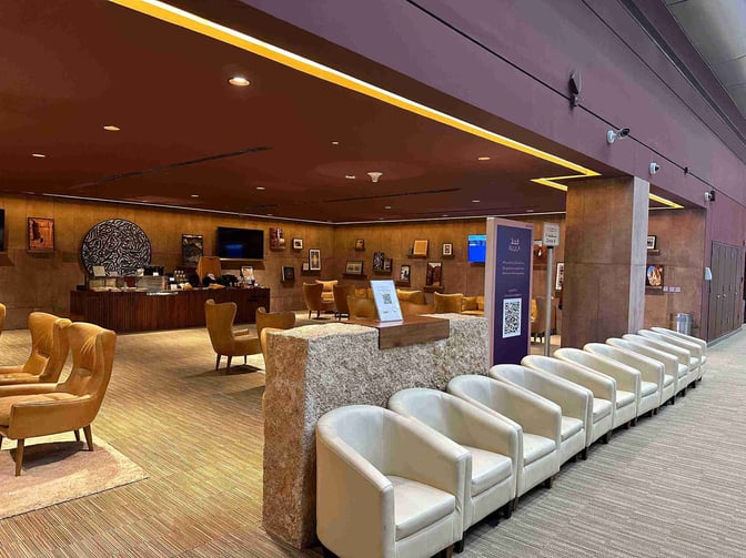 The Al Ula Lounge at Prince Abdul Majeed bin Abdulaziz Airport features comfortable seating and a self-serve refreshment area with artwork displays.