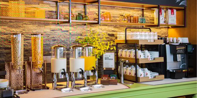The Hub Lounge at Shanghai Pudong International Airport features a self-serve breakfast station with cereal dispensers, juice, and a coffee machine.