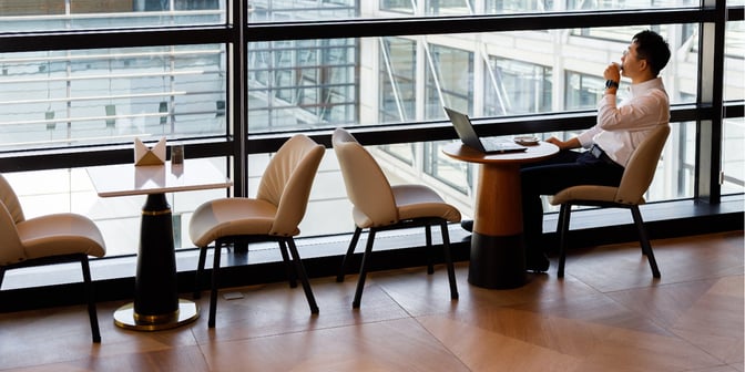 Seating area in The Hub Lounge at Shanghai Pudong International Airport offers tables with views of the airport through large windows.