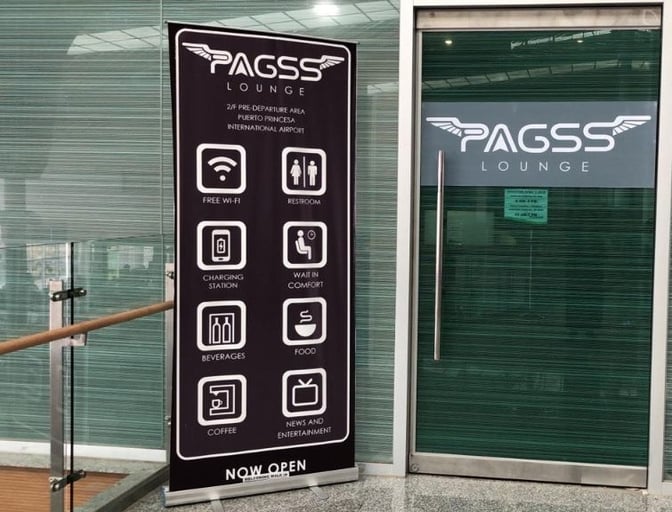 The entrance to PAGSS Lounge at Puerto Princesa International Airport features a sign highlighting amenities like free Wi-Fi, beverages, and restrooms.