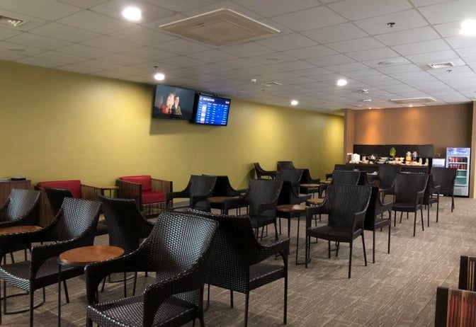 The PAGSS Lounge at Puerto Princesa International Airport features seating with small tables and a self-serve refreshment area.