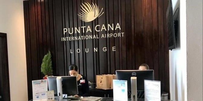 The reception area of Punta Cana International Airport Lounge features staff at a check-in desk with informational displays.