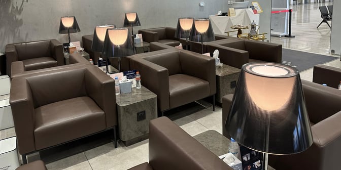The seating area at Hayyak Lounge features armchairs with side tables, lamps, and amenities like water bottles and tissues.