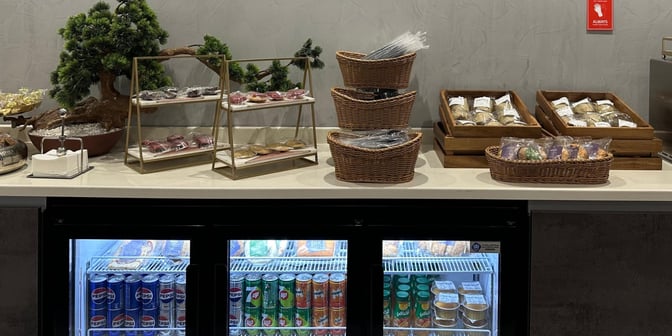 The self-serve snack station at Hayyak Lounge offers packaged snacks and a variety of chilled beverages in a refrigerated display.