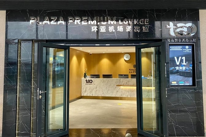 The entrance to Plaza Premium Lounge V1 at Qingdao Liuting International Airport features a reception desk and welcoming signage.