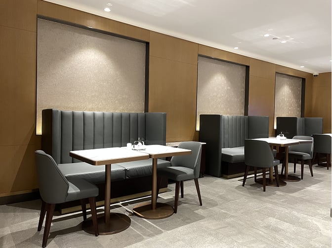 Booth seating in the Plaza Premium Lounge at Qingdao Liuting International Airport offers semi-private dining spaces with tables and chairs.