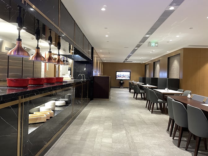 The Plaza Premium Lounge at Qingdao Liuting International Airport features a self-serve food area with seating and a television for entertainment.