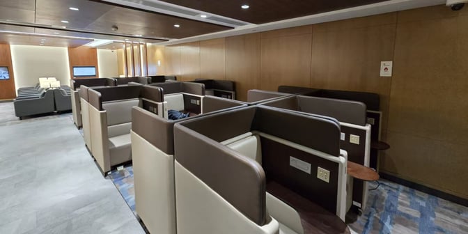 The Plaza Premium Lounge at Qingdao Liuting International Airport features semi-private booth seating with individual power outlets and small tables.