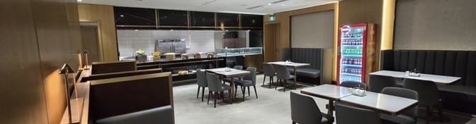 The Plaza Premium Lounge at Qingdao Liuting International Airport features a dining area with booth seating and a self-serve beverage station.