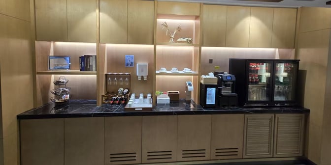 The refreshment area in Plaza Premium Lounge at Qingdao Liuting International Airport offers self-serve beverages, snacks, and a coffee machine.