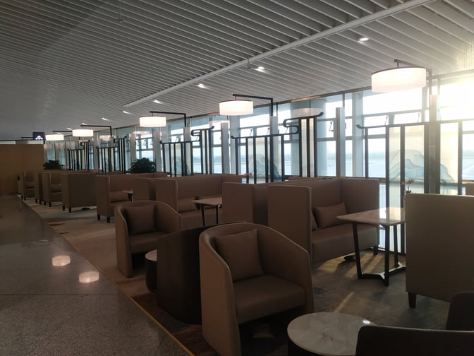 The Trovk Waiting Room at Qingdao Jiaodong International Airport features booth seating with tables, offering views of the airport exterior.