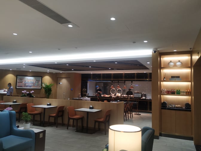 The Trovk Waiting Room at Qingdao Jiaodong International Airport features a dining area with tables, chairs, and a visible buffet counter.