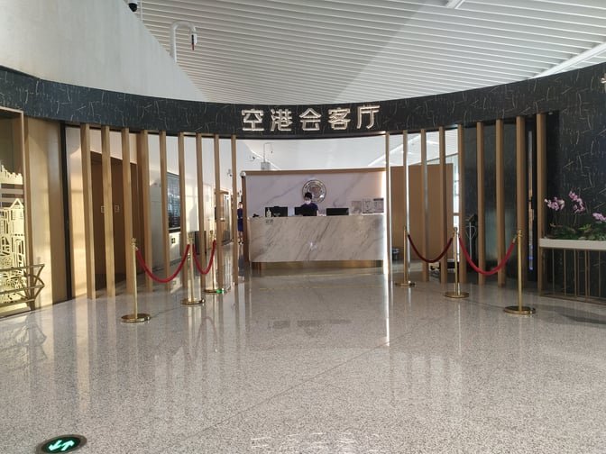 The entrance to the Trovk Waiting Room at Qingdao Jiaodong International Airport features a reception desk and decorative barriers.