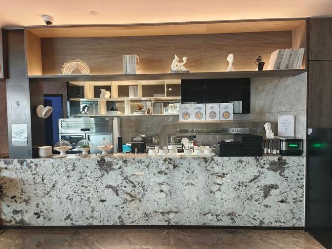 The food service area in the International VIP Club 5 at Qingdao Jiaodong Airport features a counter with covered dishes and utensils.