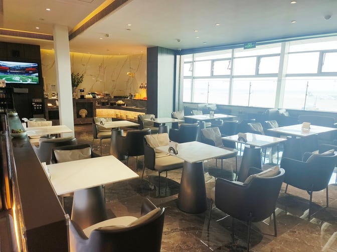 The seating area in the VIP Club 5 at Qingdao Jiaodong International Airport features tables and chairs with airport views.
