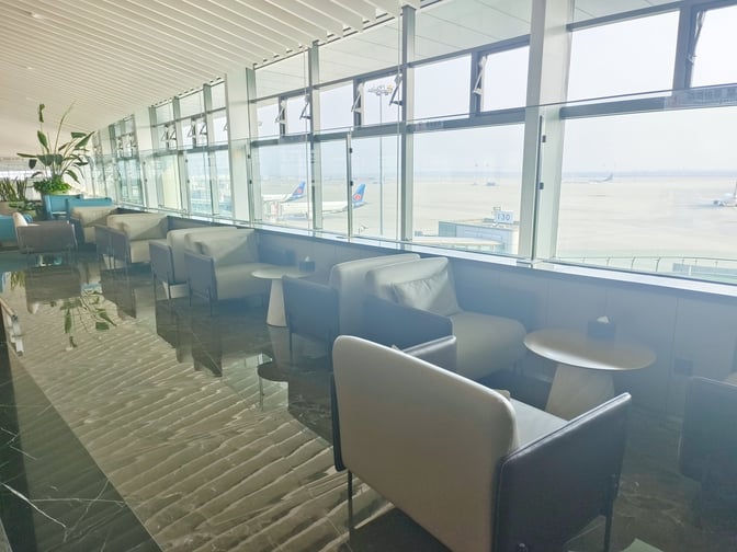 Seating in the VIP Club 5 at Qingdao Jiaodong International Airport offers comfortable chairs with tables and expansive airport views.
