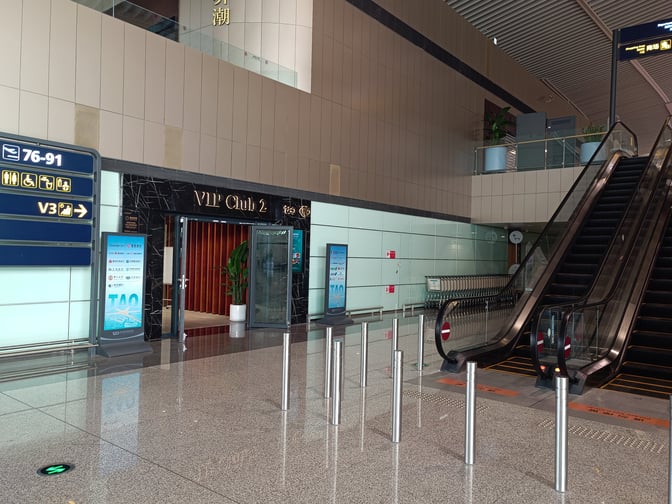 The entrance to VIP Club 2 at Qingdao Liuting International Airport is located near an escalator and directional signage.