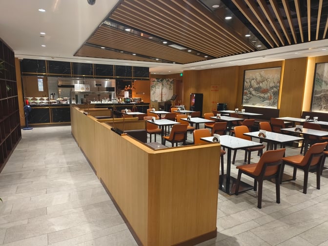 The dining area at International VIP CLUB2 in Qingdao Liuting Airport features table seating and a self-serve food station.