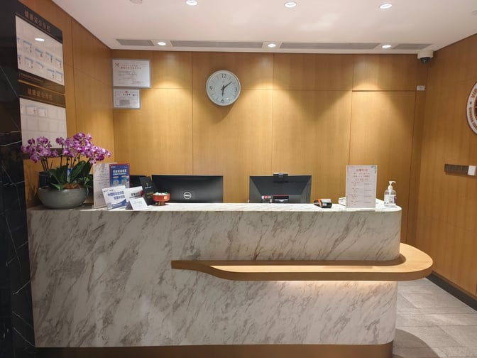 The reception desk at International VIP CLUB2 in Qingdao Liuting International Airport features informational brochures and a clock on the wall.