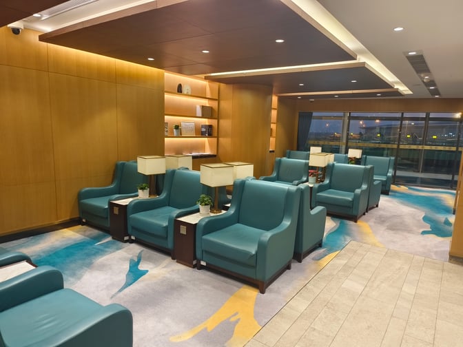 The seating area in the International VIP CLUB2 lounge at Qingdao Liuting Airport offers armchairs with side tables and airport views.