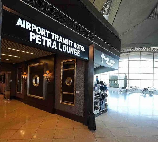 The entrance to Petra Lounge at Queen Alia International Airport features a sign for the Airport Transit Hotel and decorative wall mirrors.