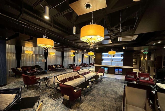 The Petra Lounge at Queen Alia International Airport features a spacious seating area with sofas and armchairs, adjacent to a refreshment station.