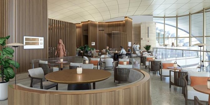 The AMWAJ Lounge at Red Sea International Airport features spacious seating areas with tables, offering views of the terminal through large windows.
