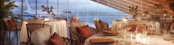 The AMWAJ Lounge at Red Sea International Airport features dining tables with runway views, offering a comfortable seating area for travelers.