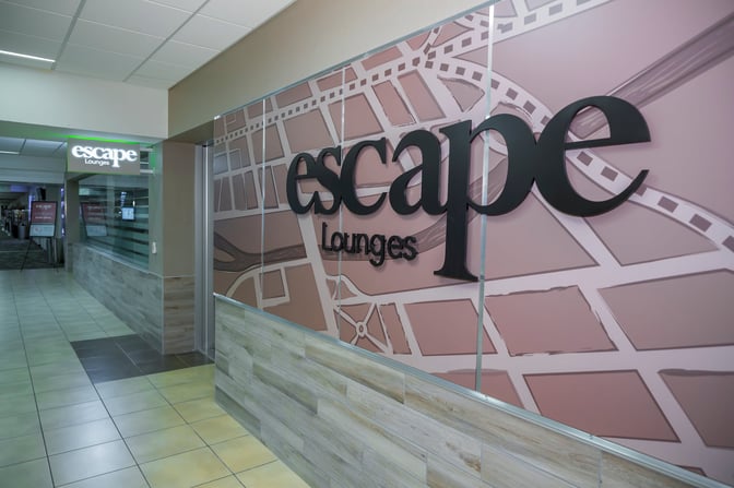 The entrance to the Escape Lounge at Reno–Tahoe International Airport features a prominent sign and is located in a tiled corridor.