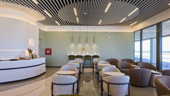 The Goldair Handling Lounge at Rhodes International Airport features a seating area with tables and chairs, offering airport views.