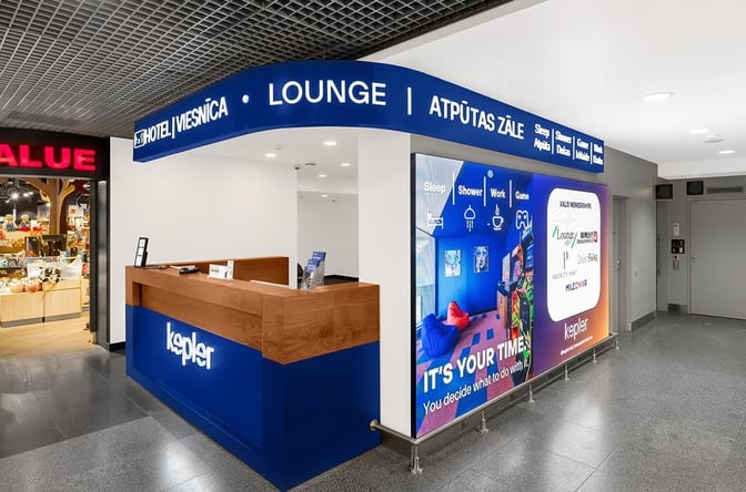 The entrance to the Kepler Club Lounge at Riga International Airport features a reception desk and promotional signage highlighting lounge amenities.