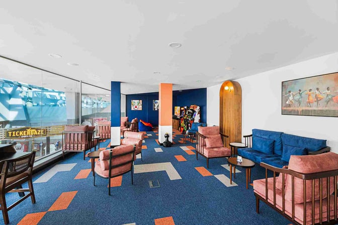 The seating area in Kepler Club at Riga International Airport features comfortable chairs and couches with views of the terminal.