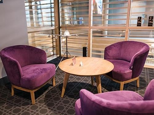 Seating area in the Primeclass Business Lounge at Riga International Airport features comfortable chairs around a small wooden table.