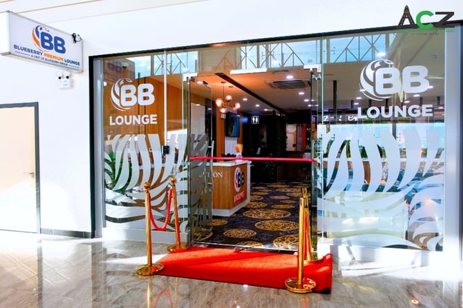 The entrance to the Blueberry Premium Lounge at Robert Mugabe International Airport features glass doors and a reception area.