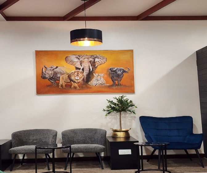 Seating area at Vhakacha Lounge features comfortable chairs and tables, with wildlife artwork enhancing the ambiance at Robert Mugabe International Airport.