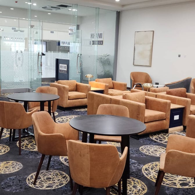 The Khami Lounge at Robert Mugabe International Airport features comfortable seating with tables, providing a relaxing space for travelers.