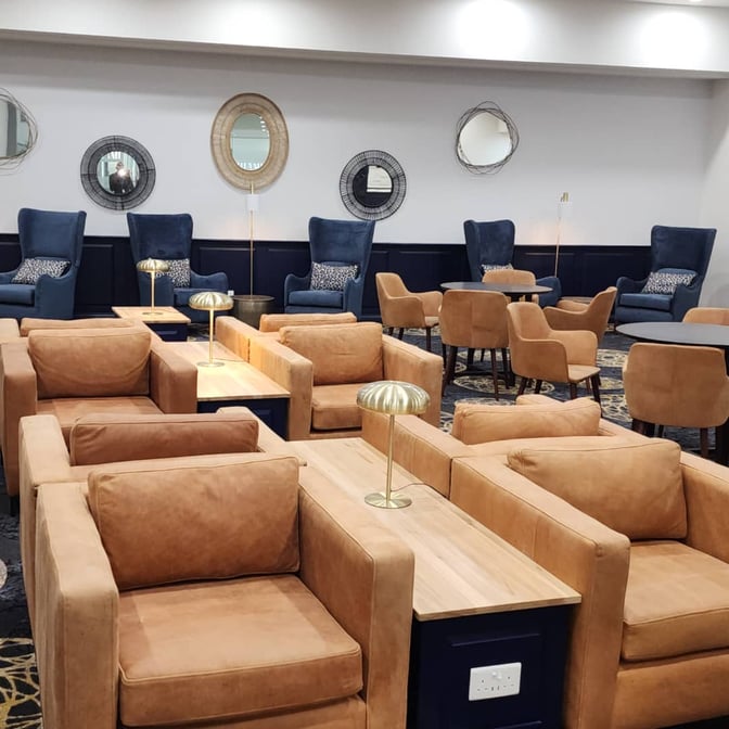 The seating area in Khami Lounge at Robert Mugabe International Airport features armchairs and tables with individual lamps for travelers.