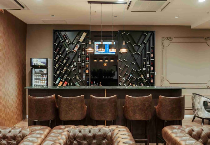 The bar at the Premium Luxury Lounge in Robert Mugabe International Airport features a variety of displayed spirits and leather bar stools.