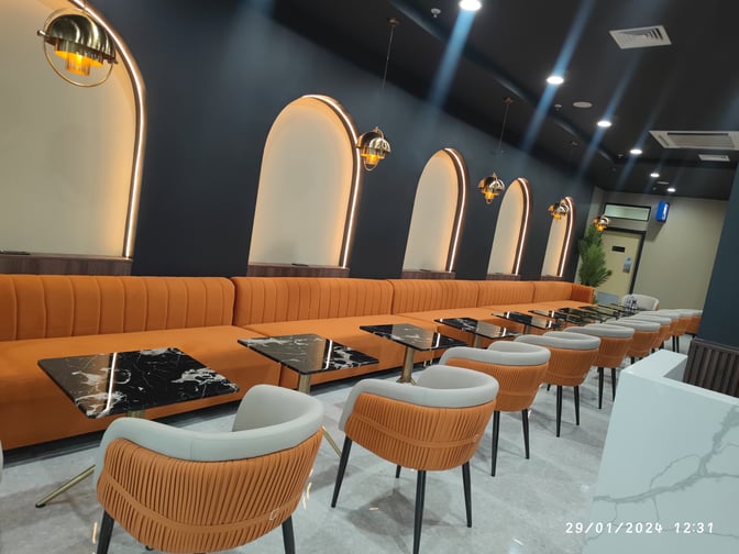 The seating area at Robert Mugabe International Airport lounge features long upholstered benches and individual tables for passenger comfort.