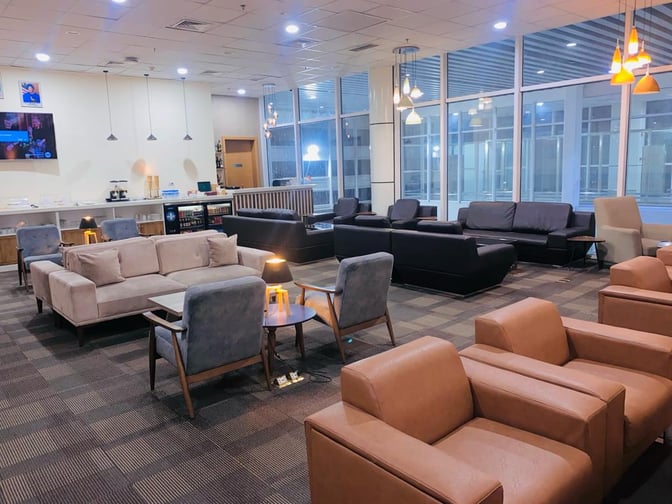 The Sanbra Business & Priority Lounge at Roberts International Airport features a seating area with sofas and a self-serve beverage station.