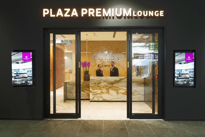 The entrance to the Plaza Premium Lounge at Leonardo da Vinci-Fiumicino Airport features a reception desk and digital displays.