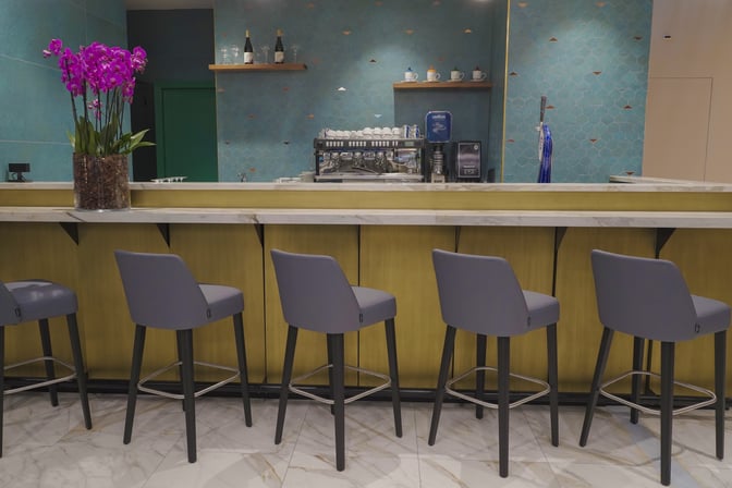 The bar area in the Plaza Premium Lounge at Leonardo da Vinci-Fiumicino Airport features seating and a coffee machine.