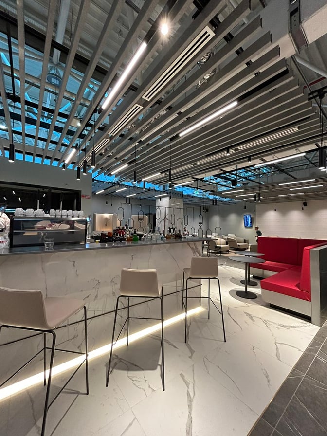 The Primeclass Lounge at Leonardo da Vinci-Fiumicino Airport features a bar with high stools and adjacent booth seating for travelers.