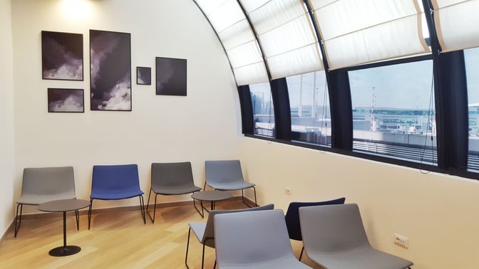 Seating area in Prima Vista Lounge Domus at Leonardo da Vinci-Fiumicino Airport offers chairs and tables with airport views.