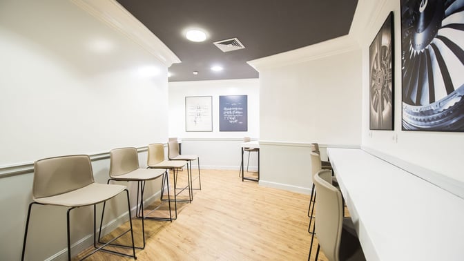 The Prima Vista Lounge at Leonardo da Vinci-Fiumicino Airport features a seating area with high chairs and wall-mounted artwork.