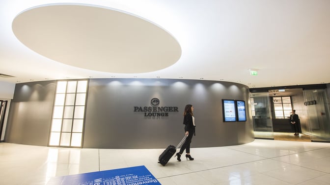 The entrance to the Passenger Lounge at Leonardo da Vinci-Fiumicino Airport features a glass door and digital information screens.