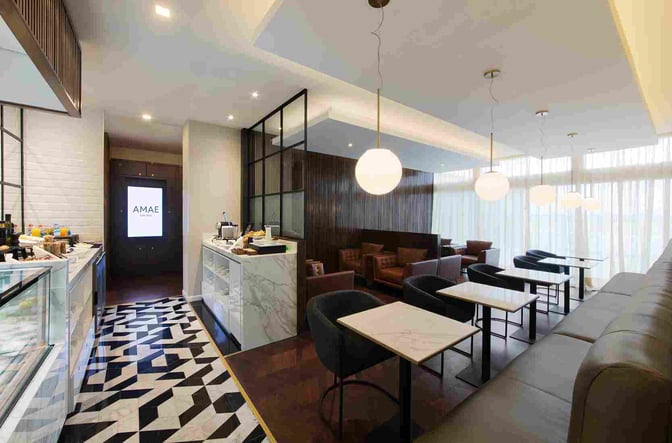 The AMAE Lounge at Rosario Airport features a seating area with tables and chairs, alongside a self-serve food station.