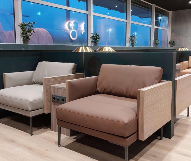 Seating area at Prima Vista Lounge, Rotterdam The Hague Airport, features comfortable chairs with power outlets and views of the tarmac.
